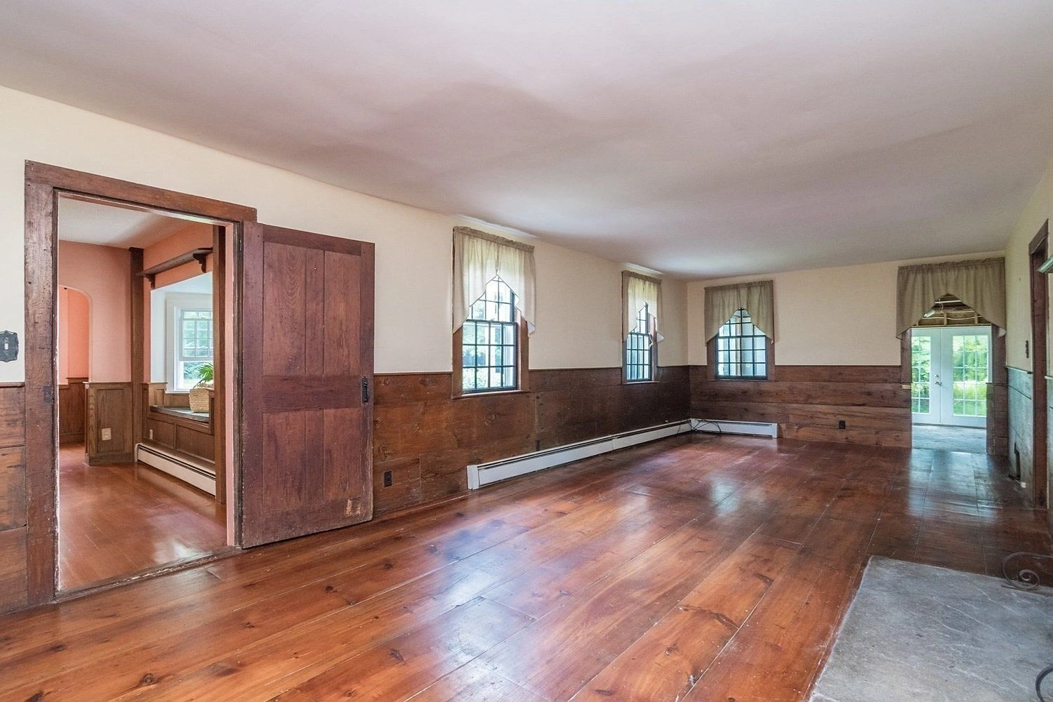 Spacious room with wide board flooring and wainscoting